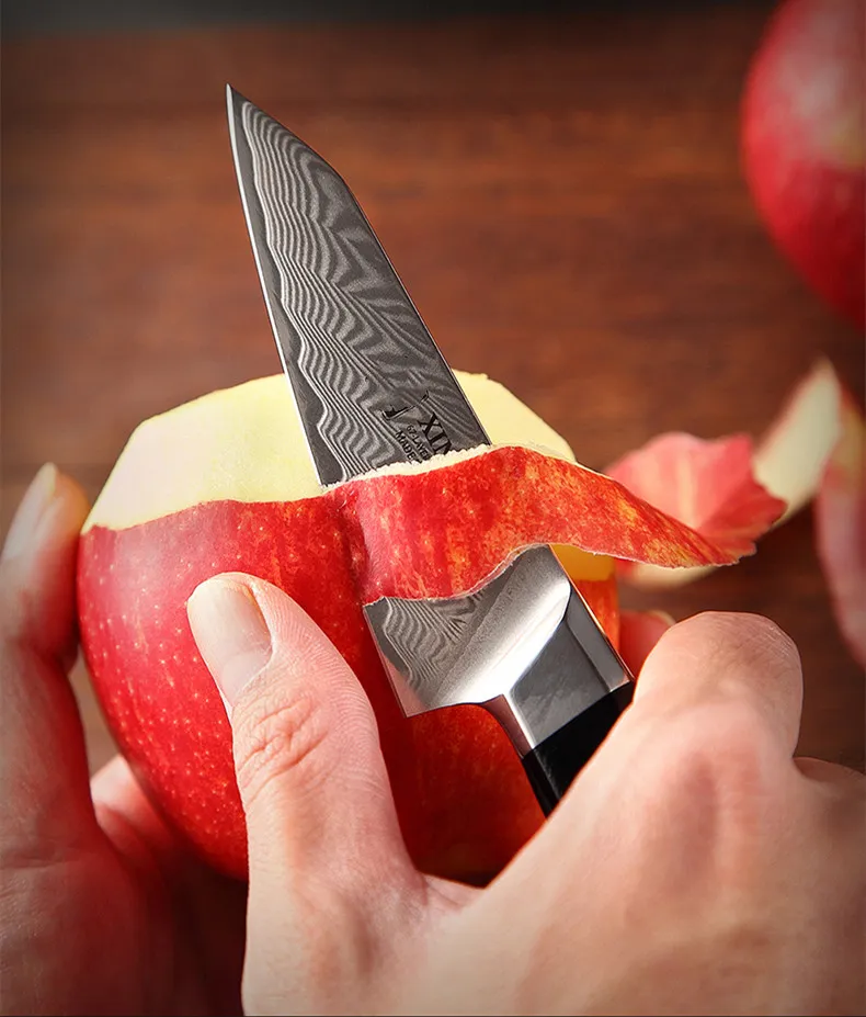 A damascus paring knife peeling an apple